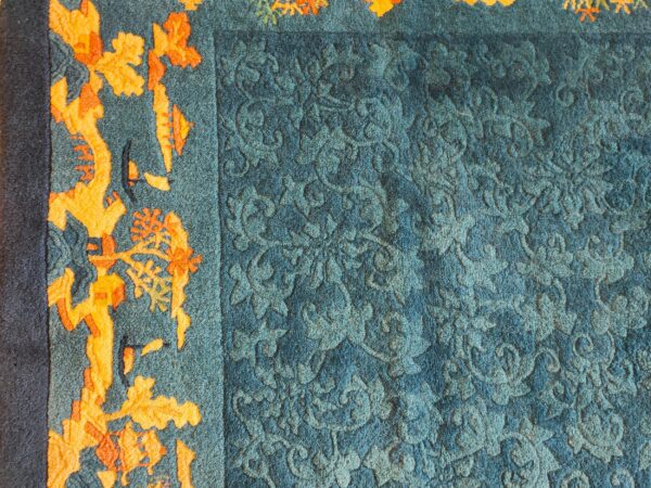 Antique peking small scatter size wool blue, green rug 2 Textured teal rug features an embossed tone-on-tone floral field next to a vibrant orange abstract border and navy edge.