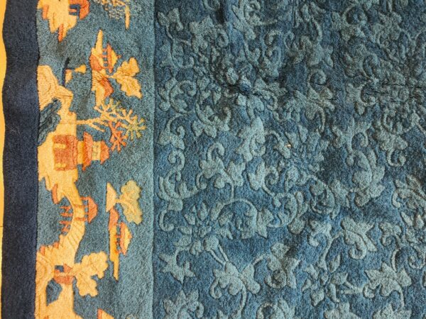 Antique peking small scatter size wool blue, green rug 3 Close view of a blue rug with a carved pile floral field and an orange patterned border.
