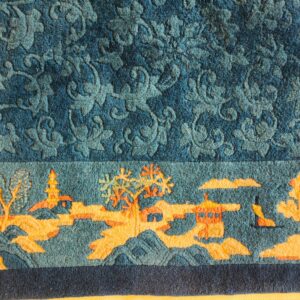 Textured blue rug with a carved floral field above an orange and blue scenic landscape border.