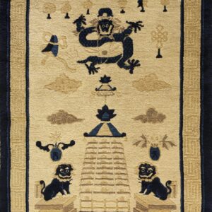 Cream rug featuring a central navy blue creature motif, taupe clouds, and an ornate tan meander border.