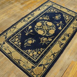 Traditional navy rug with beige and teal floral designs on distressed plank hardwood flooring.