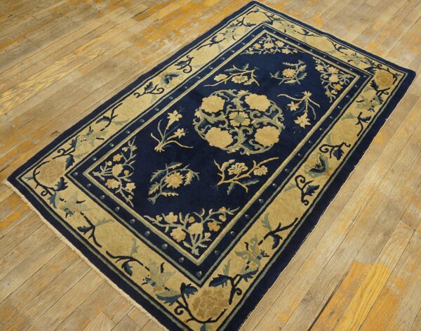 Traditional navy rug with beige and teal floral designs on distressed plank hardwood flooring.