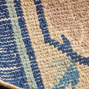 A rug detail contrasts tan high pile texture with a geometric low loop border in blue and beige.