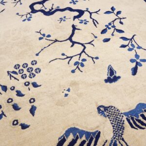 Cream rug with indigo Chinoiserie flowering tree and bird design displayed on hardwood flooring.