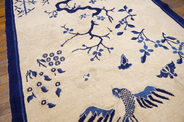 Cream rug with indigo chinoiserie flowering tree and bird design displayed on hardwood flooring.