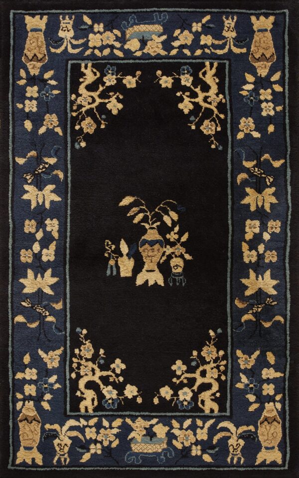 Black field rug with golden vase and floral motifs surrounded by a wide, indigo border pattern.