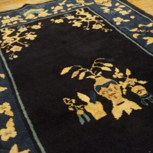 Dark blue rug detail with contrasting beige floral patterns and an ornate border on wooden flooring.