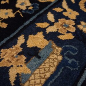 Textured, high-pile rug detail showing tan floral patterns on a dark blue field with light blue borders.
