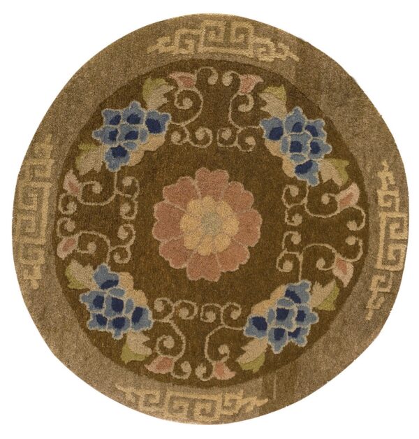 Round brown rug with dark blue, pink, and tan floral designs and a geometric border.