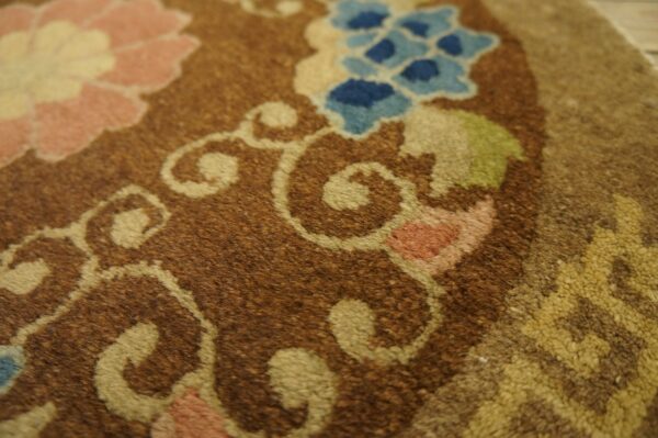 Brown rug detail showing textured pile with pink, blue, green, and tan floral scrollwork.