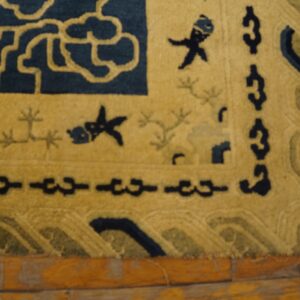 High-pile rug in navy and yellow with cloud and fish motifs rests on distressed wood flooring.