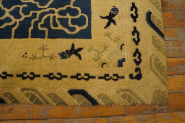 High-pile rug in navy and yellow with cloud and fish motifs rests on distressed wood flooring.