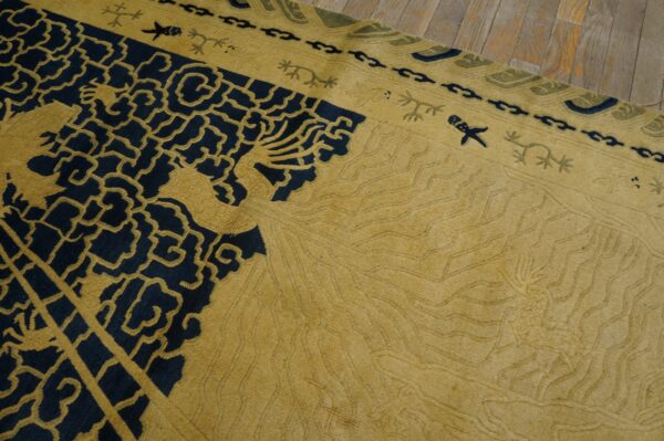 Carved gold and navy rug featuring detailed traditional patterns, viewed close-up on a wood floor.