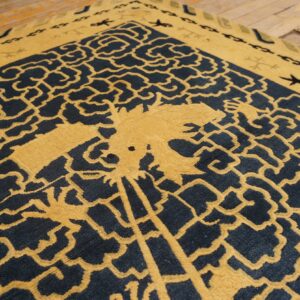 High-contrast navy and mustard rug with a detailed, stylized central design resting on hardwood planks.
