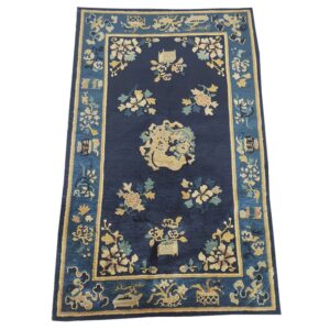 Navy area rug with an ornate gold and teal floral pattern and a complex medium blue border.