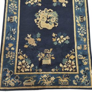 Dark blue rug featuring gold and sage floral motifs, a central medallion, and a detailed teal blue border.
