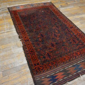 Dark runner rug featuring complex red and navy geometric patterns rests on heavily distressed wood flooring.