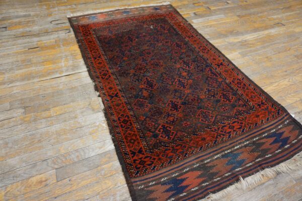 Dark runner rug featuring complex red and navy geometric patterns rests on heavily distressed wood flooring.