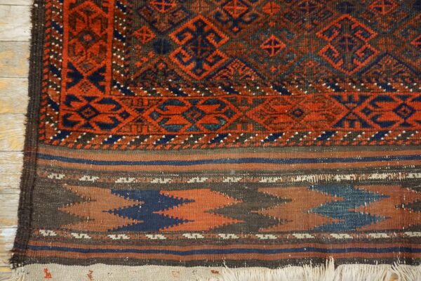 Red, blue, and brown geometric pile rug detail transitions to a flatweave skirt on wooden floorboards.