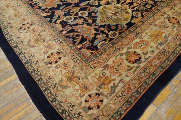 A detailed corner view of a densely patterned rug with navy blue, cream, and rust colors on wood floor.