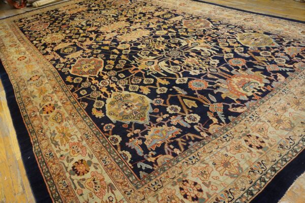 Ornate navy rug with colorful motifs and a contrasting light beige border rests on wood planks.