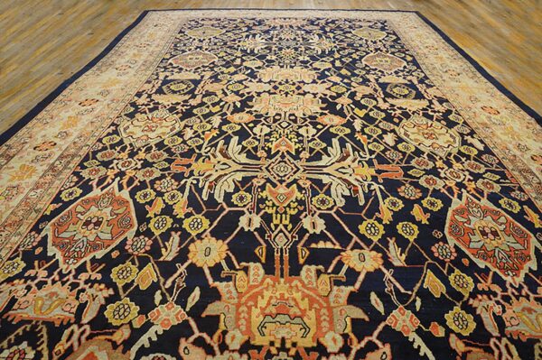 Intricate navy rug featuring gold and orange designs with a wide cream border on wooden floorboards.