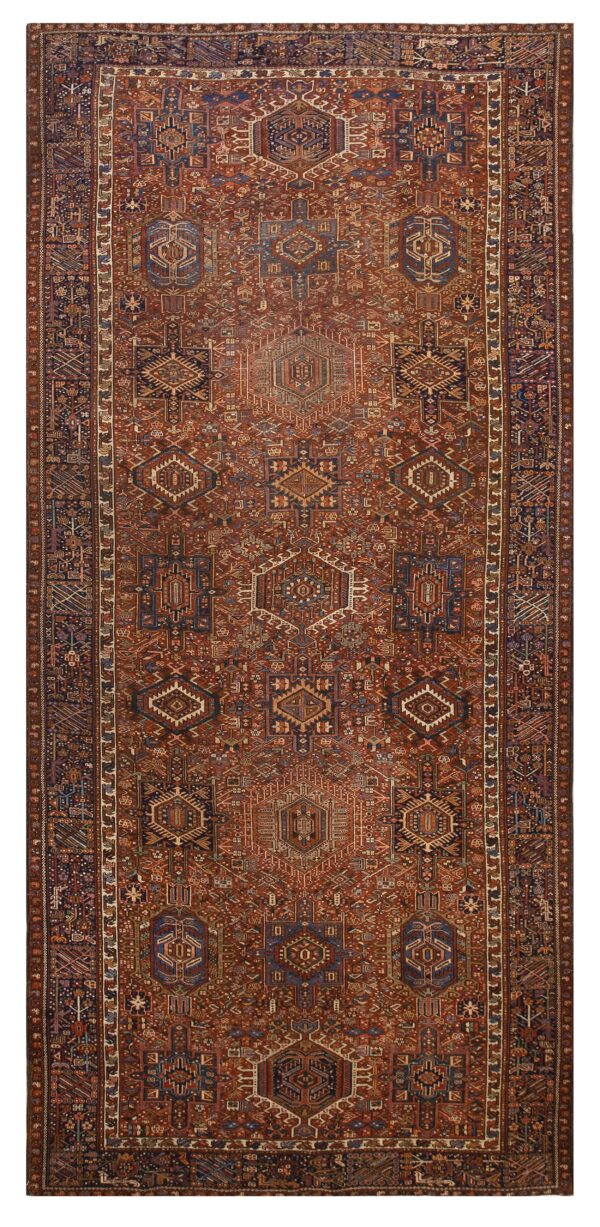 Vertical runner rug with a dense, repeating geometric tribal pattern in rich rust, dark blue, and cream colors.