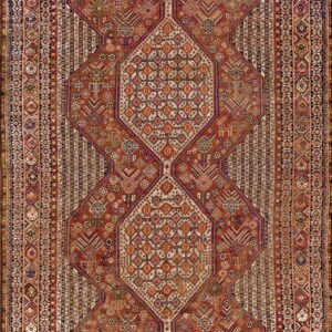 Rust-red rug displaying three large, stacked diamond medallions against a heavily patterned field and striped borders.