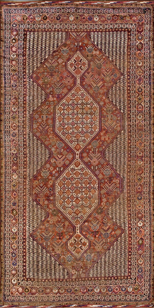 Rust-red rug displaying three large, stacked diamond medallions against a heavily patterned field and striped borders.