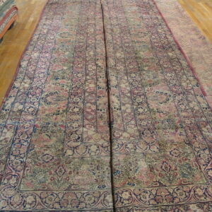 Two large, low-pile rugs with intricate beige, pink, and navy floral patterns laid side-by-side on wood planks.