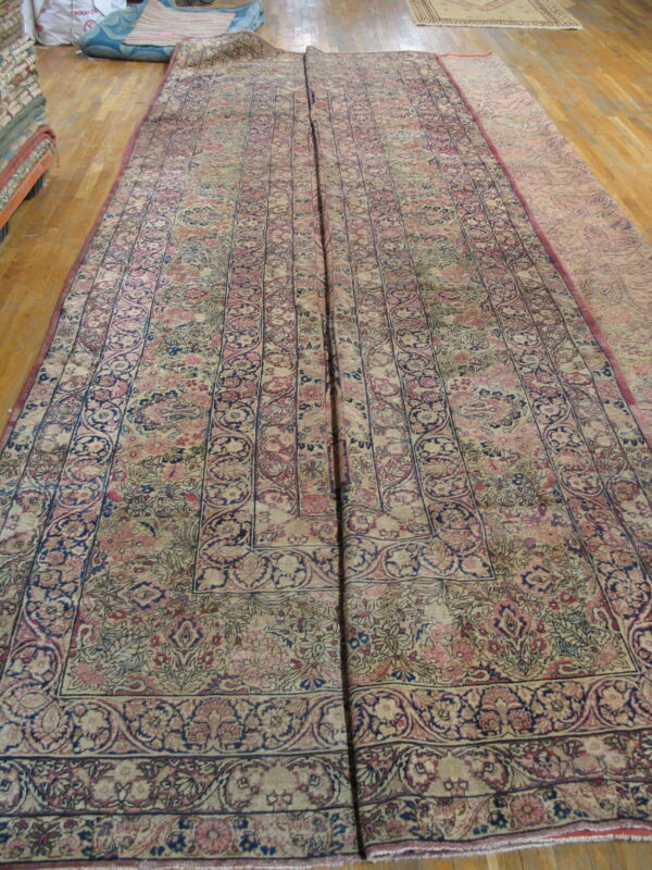 Two large, low-pile rugs with intricate beige, pink, and navy floral patterns laid side-by-side on wood planks.