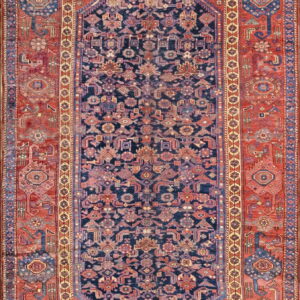 Upright shot of a detailed navy and terracotta geometric rug with a central diamond medallion design.