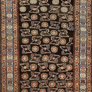Dark runner rug featuring geometric tribal patterns in red, blue, and beige on a dark brown field.