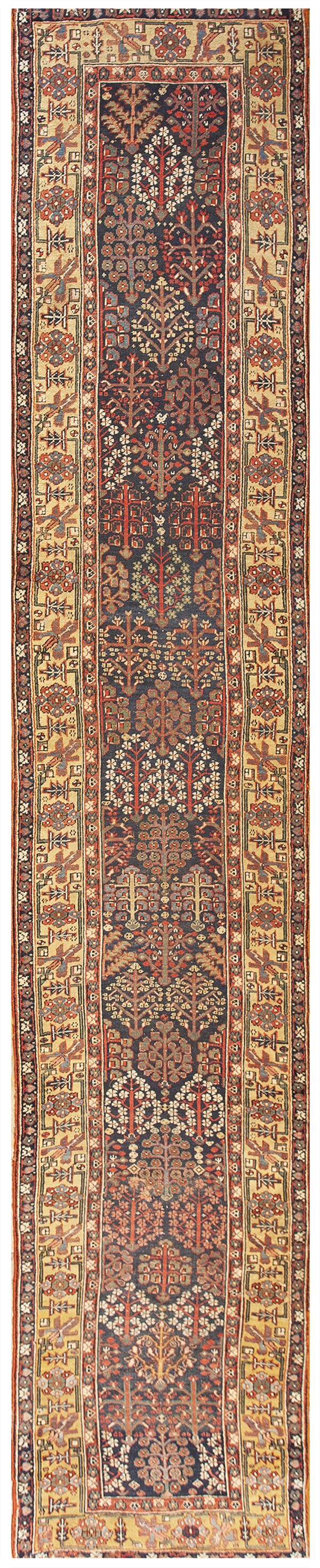 A long runner rug with a dark blue field displaying stylized trees and a light beige geometric border.