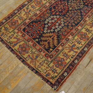 Navy, red, and gold patterned rug resting on distressed wooden floorboards with yellow accents.