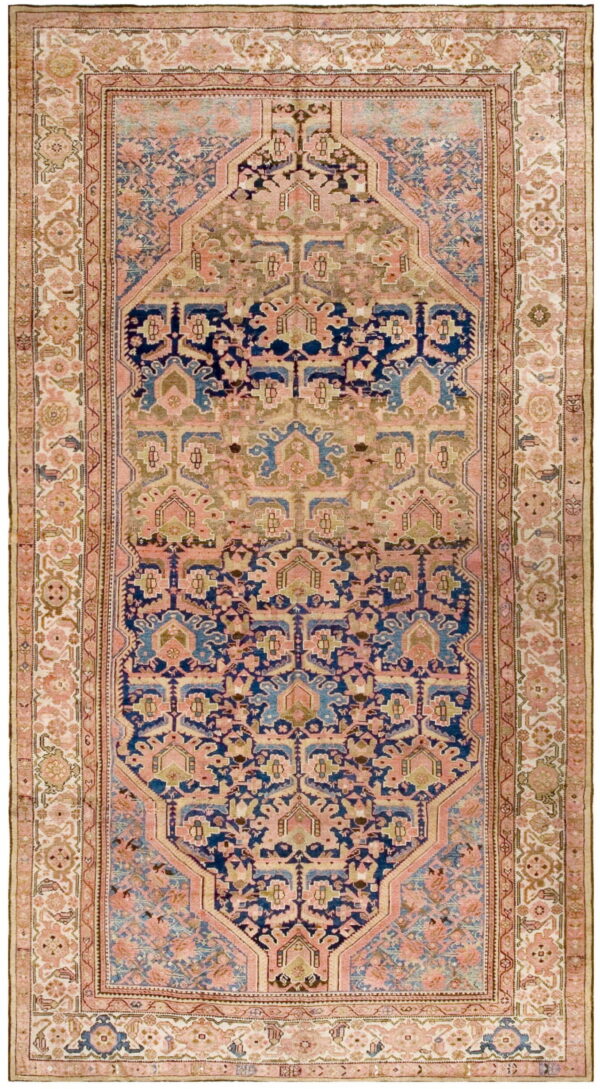 Ornate traditional rug with a geometric medallion pattern featuring navy blue, pink, and olive tones.
