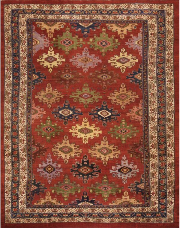 Red field rug patterned with large geometric motifs in olive, navy, beige, and lavender tones.
