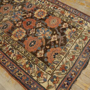 Low-pile rug with intricate coral and blue floral designs set against a dark brown field on light wood floor.
