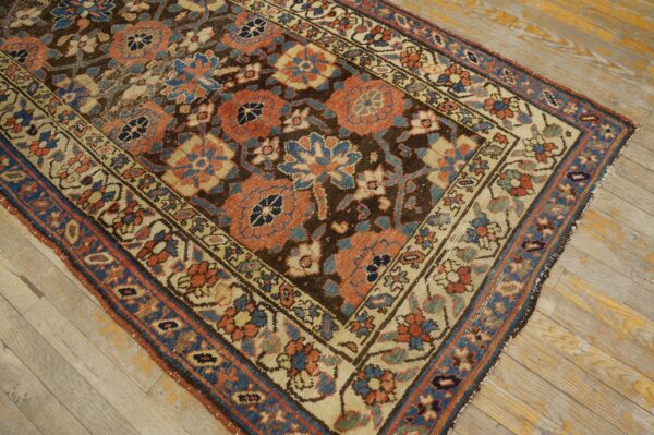 Low-pile rug with intricate coral and blue floral designs set against a dark brown field on light wood floor.