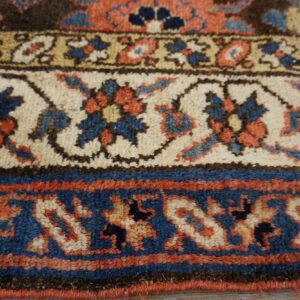 Low-pile rug borders show detailed traditional patterns in deep blue, cream, terracotta, and brown colors.