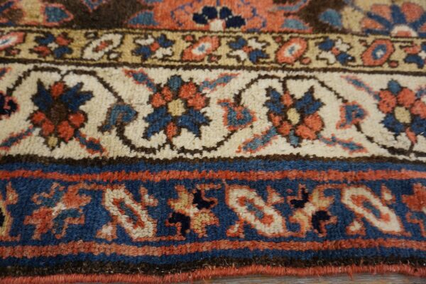 Low-pile rug borders show detailed traditional patterns in deep blue, cream, terracotta, and brown colors.