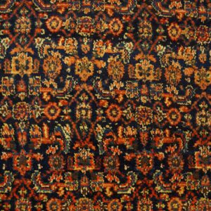 High-pile rug surface showing a dense traditional pattern in navy, rust red, and orange.