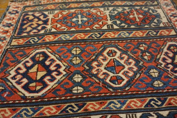 Low-pile tribal rug detail with deep red, indigo, and ivory geometric patterns and thick stripes.