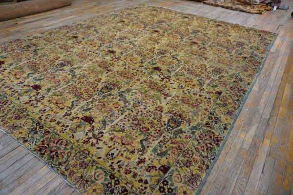 Intricately patterned rug in gold, maroon, blue, and pink covers worn wooden plank flooring.