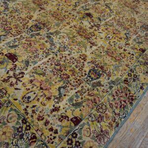 Multicolored rug with dense yellow and burgundy floral patterns borders light wood plank flooring.