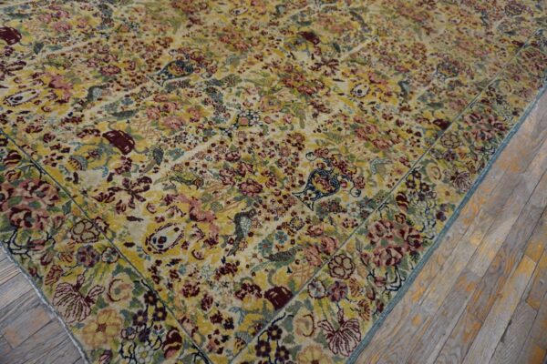 Multicolored rug with dense yellow and burgundy floral patterns borders light wood plank flooring.