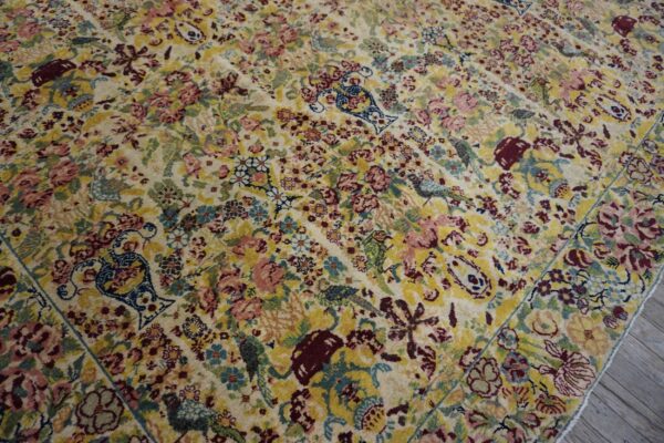 Detailed cream rug with a dense all-over pattern of colorful florals, birds, and vases.