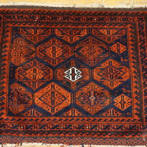 Navy and rust geometric patterned rug featuring repeating medallions on light wooden flooring.