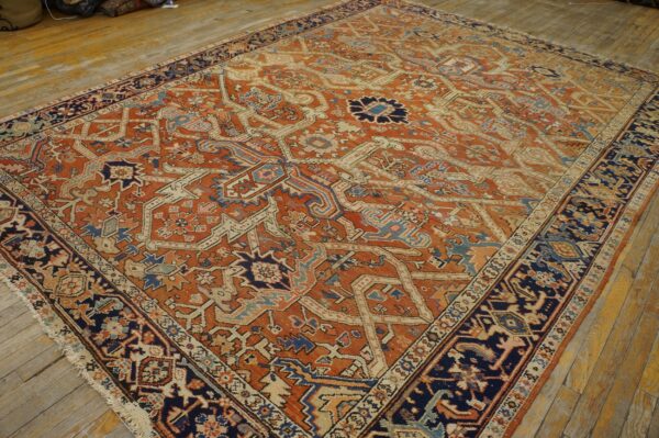 Rust-colored rug featuring a complex navy, cream, and blue geometric medallion pattern on hardwood.