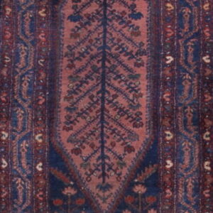 A narrow dark blue and rust runner rug with repeating stylized tree and geometric patterns.